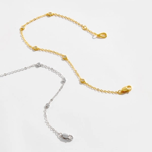 Detailed view of two delicate silver and gold chain bracelets with inlaid round crystals