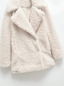 Nahaufnahme der cremefarbenen Teddyfell-Textur und Kragendetails am Oversize-Mantel