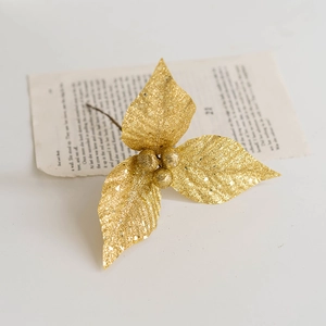 Golden glitter artificial Christmas leaves with berries on vintage book page
