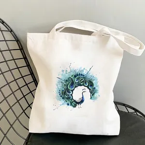 Nahaufnahme des Pfau-Kunstdrucks auf einem weißen Canvas-Shopper auf einem Designstuhl