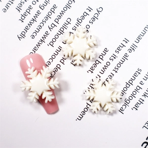 Makroansicht von weißen Schneeflocken-Resin-Charms auf rosa Nägeln für Nailart