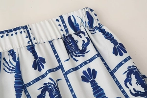 Detail view of the elastic waistband on white trousers with blue lobster print patterns