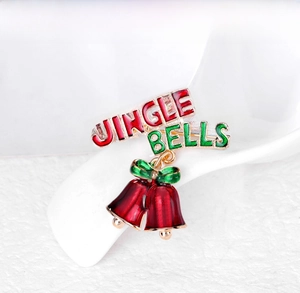 Detail of a Christmas bell brooch with red enamel, green bows and Jingle Bells text