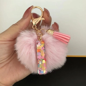 Detail of pink resin pendant with heart sequins, plush pompom and tassel keychain