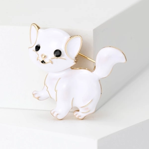 Detailed view of white enamel cat brooch with gold edges and black eyes on stand