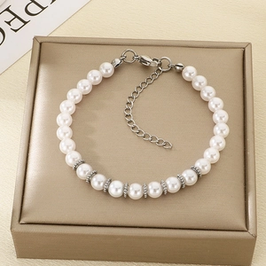 Détail d'un bracelet en perles blanches avec fermoir argenté sur un écrin à bijoux