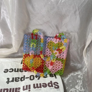 Detailed view of colorful acrylic beads and floral patterns on a handmade woven tote bag