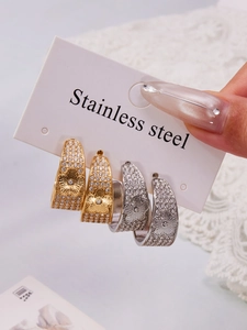 Detailed macro of C-shaped floral earrings in gold and silver with zircon inlays