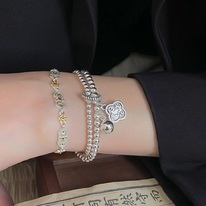Detailed macro of a vintage silver bracelet featuring enamel flowers and Ruyi charm