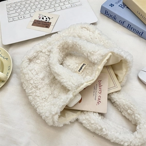 Detail of white plush faux shearling handbag with soft curly texture and branded label