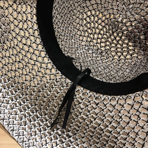 Détail du chapeau de paille tissé ajouré avec bandeau noir et cordon de serrage réglable