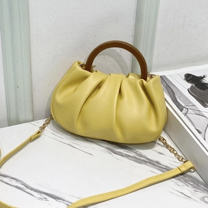 Yellow ruched cloud bag featuring dark wood round handles and a gold chain strap