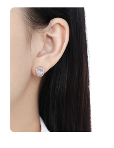 Dettaglio dell'orecchino geometrico in argento S925 con opale rosa indossato sull'orecchio