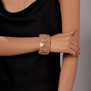 Macro shot of a chunky amber marble resin cuff bracelet on a model wearing black