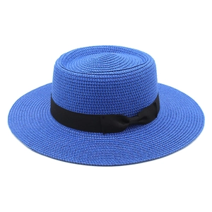 Detail of royal blue boater hat with fine weave texture and elegant black ribbon bow