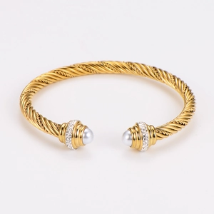 Detailed close-up of golden cable wire bracelet with pearl inlay and diamond accents