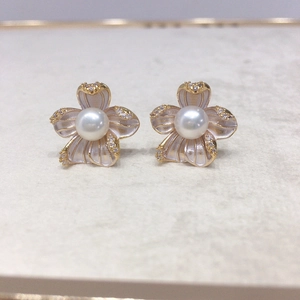 Macro detail of gold flower earrings with white freshwater pearls and zircons