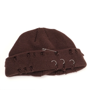 Detail of coffee knit beanie featuring metallic silver rings and safety pin decor