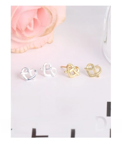 Detail view of interlocking heart studs in silver and gold with tiny clear zircon stones