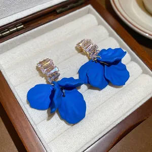 Klein Blue petal earrings with rectangular zircon studs on beige striped velvet lining
