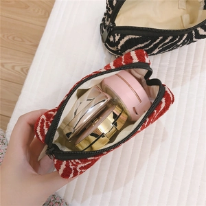 Detail of boat-shaped knit makeup bag showing interior capacity with cosmetic cases