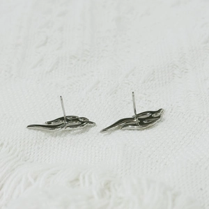 Polished silver flame-shaped earrings with tassel design on white knit background