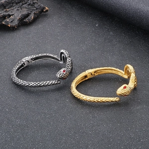 Detailed view of snake bracelet scales and red gemstone eyes in silver and gold finish