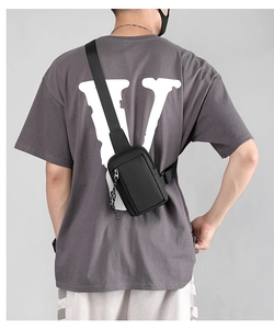 Rear view of a model wearing a compact black waterproof sling bag with woven zipper puller