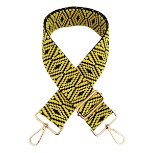Détail d'une bandoulière tissée jaune et noire avec motifs losanges et crochets dorés