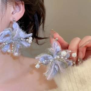 Macro detail of plush yarn flower earrings with faux pearls and silver bead accents