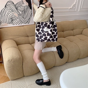Detail of corduroy heart print tote bag worn over the shoulder in a cozy interior setting