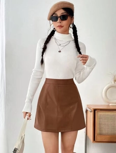 Detail of high-waist brown leather A-line skirt paired with a white turtleneck sweater