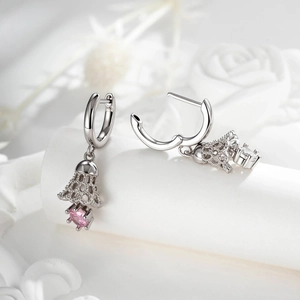 Hollow Christmas bell earrings in silver with pink gemstones on white display