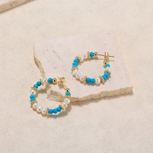 Detail of bohemian hoop earrings with natural pearls and turquoise beads on stone
