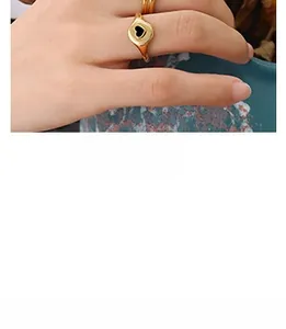 Close-up of golden ring with heart design and black enamel center worn on index finger