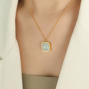 Elegant gold necklace with square light green jade pendant worn by a model