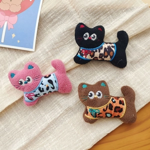 Three plush cat brooches with leopard print outfits in black, pink, and brown colors