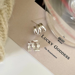 Macro detail of triple-layered sterling silver stud earrings on a textured background