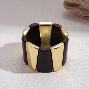 Close-up of geometric gold metal and brown resin segments on a stretch bracelet