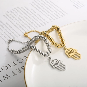 Detail of gold and silver beaded Hamsa hand bracelets with heart charms on book