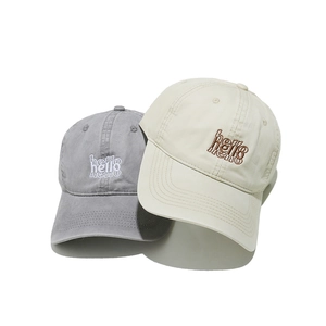 Detail showing embroidered hello text on grey and beige cotton baseball caps