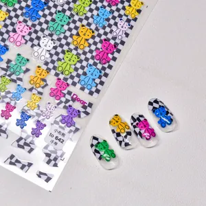 Close-up of 3D embossed teddy bear nail stickers with blue checkerboard patterns