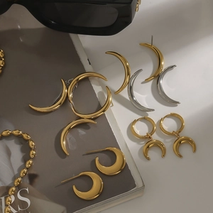 Close-up of gold and silver crescent moon earrings on a stylish fashion magazine background