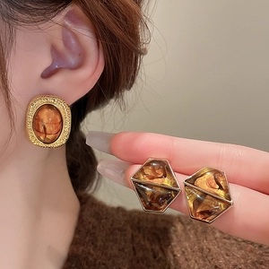 Macro detail of vintage amber resin earrings with gold-plated geometric metal frames