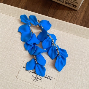 Detail of blue matte flower petal tassel earrings with gold chains in a gift box