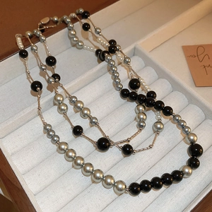 Vintage multi-layer pearl necklace with black and white beads on a gold chain