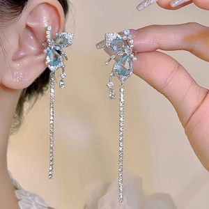 Détail du bijou d'oreille papillon argenté avec pierres bleues et gland perlé