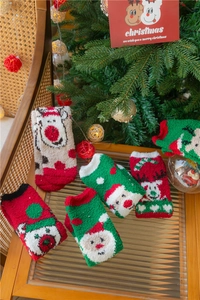 Détail de chaussettes de Noël en polaire corail avec motifs festifs sur une table
