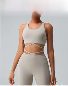 Detail of cross strap design on back of light beige sports bra and high waist yoga leggings