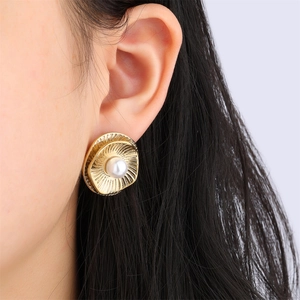 Macro shot of gold stainless steel double flower earrings featuring central white pearl